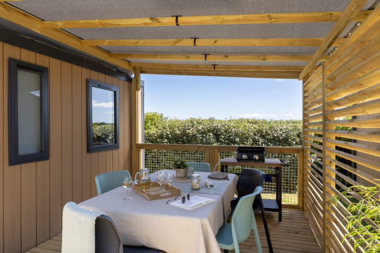 Terrasse en bois avec table dressée, vue jardin